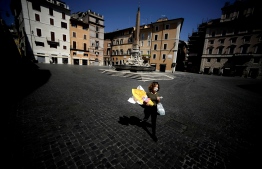 A woman carries her shopping and an Easter egg across Piazza della Rotonda in central Rome, on April 11, 2020 during the country's lockdown aimed at curbing the spread of the COVID-19 infection, caused by the novel coronavirus. (Photo by Filippo MONTEFORTE / AFP)