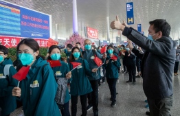 Local volunteers gesture as medical staff members (in green) from Peking Union Medical College Hospital leave at Tianhe airport in Wuhan in China's central Hubei province on April 15, 2020. - Medical staff from Peking Union Medical College Hospital is the last medical assistance team from other provinces leaving Wuhan after helping with the COVID-19 coronavirus recovery effort. (Photo by STR / AFP) / 