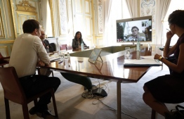 French President Emmanuel Macron (L) attends a video conference call with French virologist and President of the Research and Expertise Analysis Committee (Comite Analyse Recherche et Expertise, CARE) Francoise Barre-Sinoussi (on screen), on ongoing efforts to accelerate the development and access to vaccine and treatment against COVID-19, at the Elysee Palace in Paris on April 16, 2020, on the 31st day of a lockdown in France aimed at curbing the spread of the COVID-19 pandemic, caused by the novel coronavirus. (Photo by Yoan VALAT / POOL / AFP)