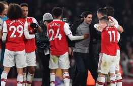 (FILES) In this file photo taken on January 1, 2020 Arsenal's Spanish head coach Mikel Arteta (C) celebrates with his players on the pitch after the English Premier League football match between Arsenal and Manchester United at the Emirates Stadium in London - Arsenal became the first Premier League club to agree a coronavirus pay cut with their players as manager Mikel Arteta and his stars slashed their wages by 12.5 percent on Monday, April 20. (Photo by Ben STANSALL / AFP) / RESTRICTED TO EDITORIAL USE. No use with unauthorized audio, video, data, fixture lists, club/league logos or 'live' services. Online in-match use limited to 120 images. An additional 40 images may be used in extra time. No video emulation. Social media in-match use limited to 120 images. An additional 40 images may be used in extra time. No use in betting publications, games or single club/league/player publications. / 