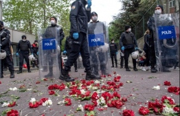 Turkish police step past carnations left by demonstrators during a May Day rally marking the international day of the worker in Istanbul, on May 1, 2020, as the country tries to curb the spread of the coronavirus, COVID-19. - Police in Istanbul detained several demonstrators who tried to march toward Istanbul's symbolic Taksim Square to mark May Day in defiance of the lockdown imposed by the government due to the coronavirus outbreak. (Photo by Bulent Kilic / AFP)