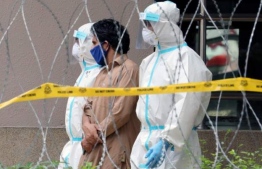 Police officers wearing protective suits pick up an undocumented immigrant, from his residence, whilst the country was under enhanced lockdown, in Kuala Lumpur, Malaysia, May 1, 2020. PHOTO: VOANEWS