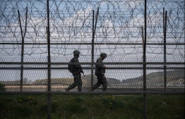 (FILES) This file photo taken on April 23, 2020 shows South Korean soldiers patrolling along a barbed wire fence Demilitarized Zone (DMZ) separating North and South Korea, on the South Korean island of Ganghwa. - North Korean troops fired multiple gunshots towards the South in the Demilitarized Zone dividing the peninsula on May 3, 2020, prompting South Korean forces to fire back, Seoul said. (Photo by Ed JONES / AFP)
