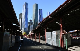 A man (L) walks through a deserted part of Melbourne's Queen Victoria Market on May 5, 2020. - Australia's economy is losing 4 billion Australian dollars (2.5 billion USD) every week its virus shutdown continues, while a million workers have already lost their jobs in the crisis, according to figures announced on May 5. (Photo by William WEST / AFP)