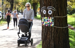 A woman pushes a pram past a giant mask and eye display stuck to a tree in Melbourne on May 8, 2020, as Australia's government unveiled a three-stage plan to get the economy back to a new "COVID-safe" normal by the end of July. However, the relaxed restrictions may have been a tad premature, as by October many parts of the country were experiencing a second wave of infections. Presently, the government's focus is on preventing a third, and possibly more deadly, 
holiday-season-induced wave. PHOTO: WILLIAM WEST / AFP 