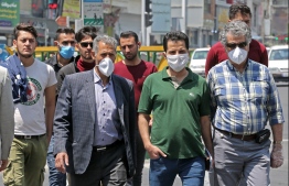 Iranian men, some wearing protective masks amid the novel coronavirus pandemic, walk by on a street of the capital Tehran, on May 09, 2020. PHOTO: ATTA KENARE / AFP