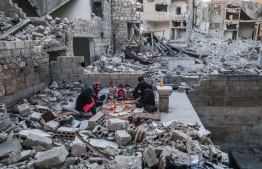 This picture taken on May 4, 2020 during the Muslim holy fasting month of Ramadan shows members of the displaced Syrian family of Tareq Abu Ziad, from the town of Ariha in the southern countryside of the Idlib province, breaking their fast together for the sunset "iftar" meal, in the midst of the rubble of their destroyed home upon their return to the town for one day after fleeing during the previous military assault by Syrian government forces and their allies. (Photo by AAREF WATAD / AFP)