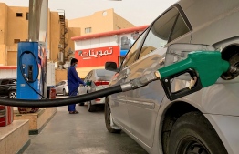 A gas station attendant refills a car at a station in the Saudi capital Riyadh on May 11, 2020. (Photo by RANIA SANJAR / AFP)