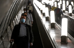People wearing face masks ride an escalator at Savyolovskaya metro station on the first day of mandatory use of masks and gloves on Moscow public transport, in Moscow on May 12, 2020, amid the coronavirus pandemic. (Photo by Kirill KUDRYAVTSEV / AFP)