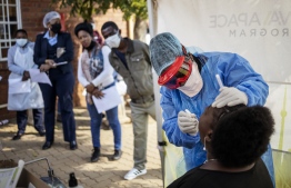 Doctors Without Borders (MSF) nurse Bhelekazi Mdlalose (2nd R), 51, performs a swab test for COVID-19 coronavirus on a health worker at the Vlakfontein Clinic in Lenasia, Johannesburg, on May 13, 2020. - Bhelekazi Mdlalose, who is employed by Doctors Without Borders (MSF), left her family and usual job in the mountain town of Rustenberg in March 2020 to support community work in Johannesburg. (Photo by Michele Spatari / AFP)