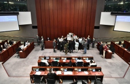 Hong Kong pro-democracy lawmakers (C) holding up placards are blocked by security as they protest during a House Committee meeting concerning the second reading of a national anthem bill, at the Legislative Council in Hong Kong on May 22, 2020. - A proposal to enact new Hong Kong security legislation was submitted to China's rubber-stamp on May 22, state media said, a move expected to fan fresh protests in the semi-autonomous financial hub. PHOTO: ANTHONY WALLACE / AFP