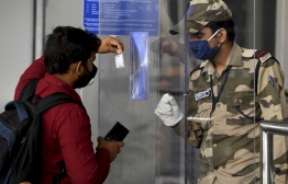 A security personnel checks the documents of a passenger standing behind a shield at the Kamaraj domestic airport during the first day of resuming of domestic flights after the government imposed a nationwide lockdown as a preventive measure against the spread of the COVID-19 coronavirus, in Chennai on May 25, 2020. - Confusion and concern reigned at Indian airports on May 25 as domestic flights tentatively resumed after two months, even as coronavirus cases continued to surge at record rates. (Photo by Arun SANKAR / AFP)