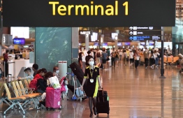 An airline flight attendant wears a face mask at Changi international airport in Singapore on January 30, 2020. - A group 92 Singaporean nationals evacuated from Wuhan, the Chinese city at the centre of a deadly virus outbreak, are due to arrive in Singapore on January 30 aboard a charter plane the Ministry of Foreign Affairs said in a statement on January 30. (Photo by Roslan RAHMAN / AFP)