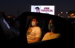 Cinema-goers in their cars attend the screening of the US musical romantic comedy film "Grease" during the reopening of the Autocine Madrid Race drive-in cinema, on May 27, 2020 in Madrid, as Spain eases lockdown measures taken to curb the spread of the COVID-19 disease caused by the novel coronavirus. - For many, it was a long-awaited chance to feel normal again, sitting in their cars belting out "Summer Nights" at Madrid's drive-in cinema on a rare night out after a 10-week lockdown. (Photo by Gabriel BOUYS / AFP)