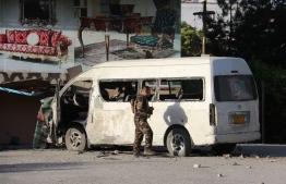 An Afghan security personnel investigates a damaged vehicle carrying employees of Khurshid TV along a roadside, at the site of a bomb blast in Kabul on May 30,2020. - A roadside bomb killed a television journalist in Kabul on May 30, soon after a top Afghan official appointed to lead peace talks with the Taliban said his team was ready for the long-delayed dialogue. (Photo by STR / AFP)