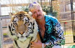 (FILES) This undated file photo courtesy of Netflix shows Joseph "Joe Exotic" Maldonado-Passage with one of his tigers. - Maldonado-Passage will have to hand over the ownership of his famous zoo to Carole Baskin, who he tried to have murdered, a court has ruled. On June 1, 2020, a judge in Oklahoma ruled that the ownership of Exotic's land must be transferred to Baskin, who runs Big Cat Rescue in Florida. Maldonado-Passage, is in jail after he was sentenced to 22 years in prison in January for the attempted murder of Baskin. (Photo by - / Netflix US / AFP) / 