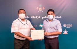 An executive of Universal Enterprises donating COVID-19 test kits to Minister of Health Abdulla Ameen. PHOTO: HEALTH MINISTRY