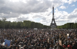 People gather on Champ de Mars in front of Eiffel Tower, in Paris on June 6, 2020, as part of 'Black Lives Matter' worldwide protests against racism and police brutality in the wake of the death of George Floyd, an unarmed black man killed while apprehended by police in Minneapolis, US. - Police banned the rally as well as a similar second one on the Champ de Mars park facing the Eiffel Tower today, saying the events were organised via social networks without official notice or consultation. But on June 2, another banned rally in Paris drew more than 20000 people in support of the family of Adama Traore, a young black man who died in police custody in 2016. (Photo by GEOFFROY VAN DER HASSELT / AFP)