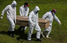 Cemetery workers wear protective suits as they carry out the burial of Edivaldo da Silva, who died at the age of 77 from COVID-19, at the Recanto da Peace Municipal Cemetery in Breves, Para state, Brazil on June 8, 2020. (Photo by TARSO SARRAF / AFP)
