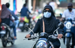 Woman on a motorcycle wearing a facemask in the capital city of Male'. PHOTO: NISHAN ALI/ MIHAARU