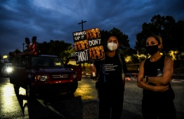 A protester shows a placard as they protest outside a burned Wendy's restaurant on the third day following Rayshard Brooks shooting death by police in the restaurant parking lot in Atlanta, Georgia June 15, 2020. - The mayor of Atlanta ordered immediate police reforms on Monday after the fatal shooting of a black man by a white police officer in the US city sparked further outrage over the deaths of African-Americans at the hands of law enforcement. (Photo by CHANDAN KHANNA / AFP)
