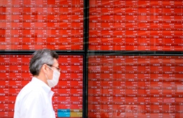 A pedestrian walks past an electronic quotation board displaying share prices of the Tokyo Stock Exchange in Tokyo on June 16, 2020. (Photo by Kazuhiro NOGI / AFP)
