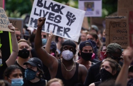 Protesters hold a "Black Lives Matter" sign and raise their fists as they march through Greenwich Village in a demonstration over the death of George Floyd by Minneapolis Police on June 19, 2020 in New York. - The US marks the end of slavery by celebrating Juneteenth, with the annual unofficial holiday taking on renewed significance as millions of Americans confront the nation's living legacy of racial injustice. (Photo by Bryan R. Smith / AFP)