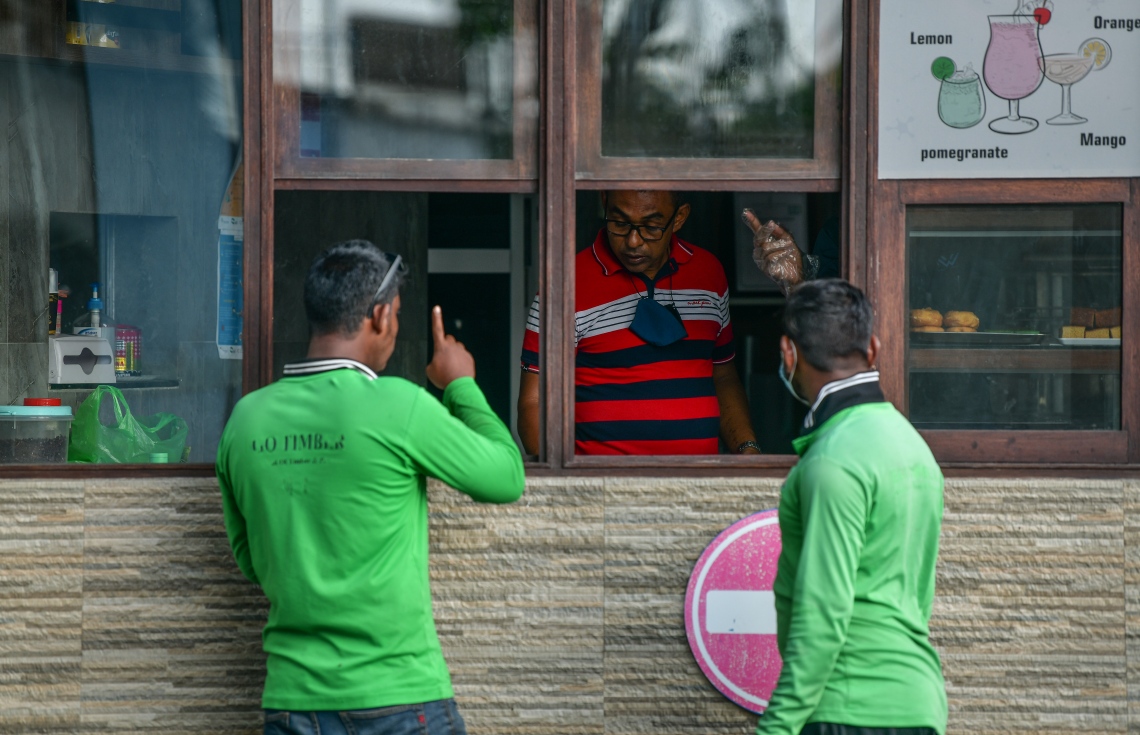 މާލެ: ޖޫން 21، 2020: މާލެ ސަރަހައްދަށް އިއުލާން ކޮށްފައިވާ ލޮކްޑައުން އަށް ލުޔެއް ދިނުމާއެކު، ކޮފީ ޝޮޕެއް ކައިރީގައި ދެމީހަކު މަޑުކޮށްލައިގެން.-- ފޮޓޯ: ނިޝާން އަލީ /މިހާރު