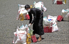 (FILES) In this file photo taken on May 17, 2020, a Yemeni youth carries a portion of food aid, distributed by Yadon Tabney development foundation, in Yemen's capital Sanaa. - On top of war and the coronavirus pandemic, Yemen faces looming economic disaster as a crisis gripping its main benefactor Saudi Arabia dents remittances and leaves state coffers running dry. (Photo by MOHAMMED HUWAIS / AFP)