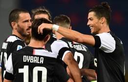 Juventus' Argentine forward Paulo Dybala (L) celebrates with Juventus' Portuguese forward Cristiano Ronaldo (R) and teammates after scoring during the Italian Serie A football match Bologna vs Juventus on June 22, 2020 at the Renato-Dall'Ara stadium in Bologna, as the country eases its lockdown aimed at curbing the spread of the COVID-19 infection, caused by the novel coronavirus. (Photo by Miguel MEDINA / AFP)