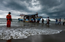 Acehnesse fishermen help evacuate a Rohingya woman from Myanmar onto the shorelines of Lancok village, in Indonesia's North Aceh Regency on June 25, 2020. - Nearly 100 Rohingya from Myanmar, including 30 children, have been rescued from a rickety wooden boat off the coast of Indonesia's Sumatra island, a maritime official said. (Photo by CHAIDEER MAHYUDDIN / AFP)