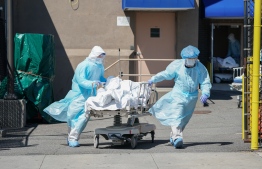 (FILES) In this file photo taken on April 06, 2020 bodies are moved to a refrigeration truck serving as a temporary morgue at Wyckoff Hospital in the Borough of Brooklyn in New York. - The global coronavirus pandemic has sparked an economic "crisis like no other," sending world GDP plunging 4.9 percent this year and wiping out $12 trillion over two years, the IMF said June 24, 2020. Worldwide business shutdowns destroyed hundreds of millions of jobs, and major economies in Europe face double-digit collapses.The prospects for recovery post-pandemic -- like the forecasts themselves -- are steeped in "pervasive uncertainty" given the unpredictable path of the virus, the IMF said in its updated World Economic Outlook. (Photo by Bryan R. Smith / AFP)