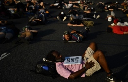 A man holding a "Black Lives Matter" sign lays on a highway along with demonstrators blocking traffic, as protests triggered by the death of George Floyd while in police custody, continue on June 23, 2020, in Washington, DC. - US President Trump on his way to Arizona warned that protesters who attempted to establish an "autonomous zone" in the US capital would be met with "serious force," following a night of protests at Lafayette Square where a crowd of protestors tried to topple the statue of Jackson. PHOTO: BRENDAN SMIALOWSKI / AFP