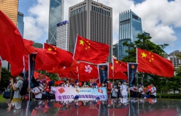 Pro-China supporters display Chinese and Hong Kong flags during a rally near the government headquarters in Hong Kong on June 30, 2020, as China passed a sweeping national security law for the city. - China passed a sweeping national security law for Hong Kong, a historic move that critics and many western governments fear will smother the finance hub's freedoms and hollow out its autonomy. (Photo by Anthony WALLACE / AFP)