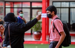 A teacher checking the temperature of a student in front of the school gate. Ministry of Education assured that precautionary measures will be set in place to ensure that students' health and safety are ensured while attending school and sitting for exams. PHOTO: NISHAN ALI/ MIHAARU
