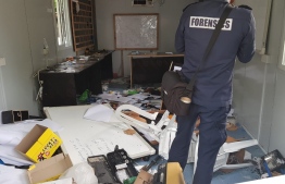 A Police officer from the Forensics department inspects a building vandalised during a protest held by expatriate officers on B. Bodufinolhu over six months of unpaid salaries. PHOTO/POLICE