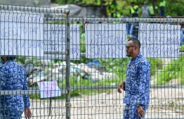 A police officer walks by the placards used during the protest staged by expatriate workers of Island Expert on July 13, 2020, over months of unpaid salaries. PHOTO: NISHAN ALI / MIHAARU