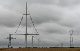 An image of the new electricity pylon installed by RTE (Electricity Transmission Network) near the town of Flers in Escrebieux, northern France on July 16, 2020. - A central mast and a triangle structure: a new type of electricity pylon is being installed during the renewal of the Avelin-Gavrelle high voltage line in Hauts-de-France. This 400,000 volt line, 30 km long, will include 45 pylons of this types and 35 classic "trellis" pylons (Right and left). (Photo by DENIS CHARLET / AFP)