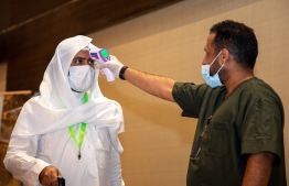 A handout picture provided by the Saudi Ministry of Hajj and Umra on July 25, 2020, shows a medical worker, mask-clad due to the COVID-19 coronavirus pandemic, checking the body temperature of travellers arriving for the annual Hajj pilgrimage at a hotel in Saudi Arabia's holy city of Mecca. - The 2020 hajj season, which has been scaled back dramatically to include only around 1,000 Muslim pilgrims as Saudi Arabia battles a coronavirus surge, is set to begin on July 29. Some 2.5 million people from all over the world usually participate in the ritual that takes place over several days, centred on the holy city of Mecca. This year's hajj will be held under strict hygiene protocols, with access limited to pilgrims under 65 years old and without any chronic illnesses. (Photo by - / Saudi Ministry of Hajj and Umra / AFP) / 