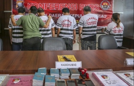 This picture taken on July 25, 2020 shows suspects (in white striped shirts), allegedly linked to the death of an Indonesian sailor aboard a Chinese fishing vessel, facing a wall while presented to the media during a police press conference in Batam. - Indonesian police have charged more suspects over the torture death of an Indonesian crew member found on July 9 in a freezer aboard a Chinese fishing vessel, authorities said on July 26. (Photo by ANDARU / AFP)