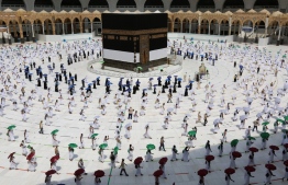 A picture taken on July 29, 2020 shows pilgrims holding coloured umbrellas along matching coloured rings separating them as a COVID-19 coronavirus pandemic measure while circumambulating around the Kaaba, Islam's holiest shrine, at the centre of the Grand Mosque in the holy city of Mecca, at the start  of the annual Muslim Hajj pilgrimage. - Mask-clad Muslim pilgrims began the annual hajj, dramatically downsized this year as the Saudi hosts strive to prevent a coronavirus outbreak during the five-day pilgrimage. The hajj, one of the five pillars of Islam and a must for able-bodied Muslims at least once in their lifetime, is usually one of the world's largest religious gatherings. (Photo by STR / AFP)