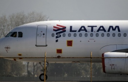 (FILES) In this file photo taken on May 26, 2020 a Latam airlines plane sits on the tarmac at Santiago International Airport, in Santiago, during the COVID-19 novel coronavirus pandemic. - Latin America's biggest airline, the Brazilian-Chilean group LATAM, is to lay off at least 2,700 crew to cope with the devastating effects of the coronavirus pandemic on the aviation industry, the company said on July 31, 2020. LATAM said it had failed to reach a deal with the aviation workers' union on reducing pay, and would therefore lay off pilots and flight attendants to keep the struggling company afloat. PHOTO: MARTIN BERNETTI / AFP