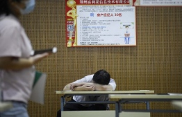 This photo taken on July 25, 2020 shows a man taking a rest during a career fair in Zhengzhou, China's Henan province. - China's economy may have rebounded sharply after a historic contraction from the coronavirus outbreak, but jobseekers face a less rosy situation -- with businesses still reeling and household savings on the rise. (Photo by WANG ZHAO / AFP) / 