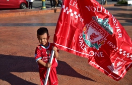 A young Thai fan of Liverpool Football Club holds a flag as he celebrates the English Premier League win during a parade in the southern Thai province of Narathiwat on July 27, 2020. - Liverpool were crowned Premier League champions without kicking a ball on July 23 as Chelsea's 2-1 win over Manchester City ended the Reds' 30-year wait to win the English title. (Photo by Madaree TOHLALA / AFP)