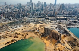An aerial view taken on August 7, 2020, shows a partial view of the port of Beirut, the damaged grain silo and the crater caused by the colossal explosion three days earlier of a huge pile of ammonium nitrate that had languished for years in a port warehouse, leaving scores of people dead or injured and causing devastation in the Lebanese capital. The city of Beirut can be seen in the background. (Photo by - / AFP)