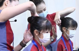 A flight attendant from Taiwan's China Airlines helps with a girl's hairdo during a 'fly to nowhere' event at the China Airlines' campus in Taoyuan City on August 8, 2020. - Faced with the coronavirus collapse in travellers, Taiwanese airlines have begun offering sight-seeing "flights to nowhere" on their passenger jets -- including flight attendant lessons for children. (Photo by Sam Yeh / AFP) / 