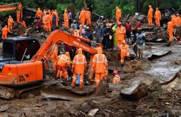Rescue workers search for missing people at a landslide site caused by heavy rains in Pettimudy, in Kerala state, on August 8, 2020. (Photo by STR / AFP)