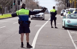 Police officers pull a car over for a licence and permit check in Melbourne on August 11, 2020, during a strict stage four lockdown of the city due to a COVID-19 coronavirus outbreak. - Victoria state reported 19 deaths from coronavirus on August 11, making it the country's equal deadliest day of the pandemic despite a fall in new case numbers. (Photo by William WEST / AFP)