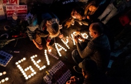 Demonstrators light candles and form a word "Belarus" outside the Belarusian embassy during a protest against the results of Belarusian presidential election in Moscow on August 12, 2020. (Photo by Dimitar DILKOFF / AFP)