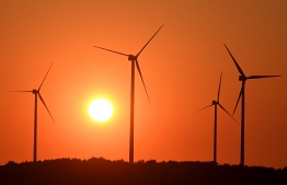 Sun sets behind wind turbines near the small villages of Neu Zauche and Straupitz, eastern Germany, at the end of a hot summer day on August 11, 2020. (Photo by Christof STACHE / AFP)